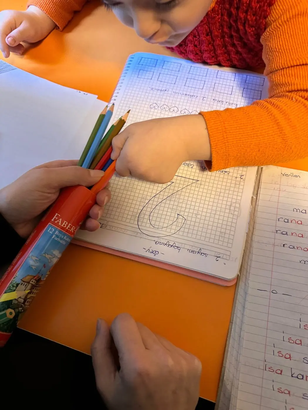 Eğitmeniyle birebir sayı yazma çalışması yapan çocuk